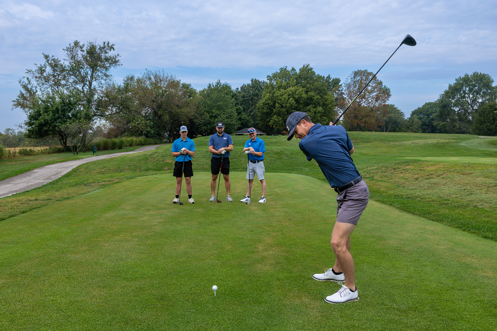 A golfer tees off while three teammates watch on a green fairway during the Ozarks Tech Foundation Golf Tournament at Hickory Hills Country Club.